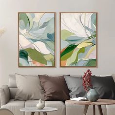 two paintings on the wall above a couch in a living room with pillows and coffee table