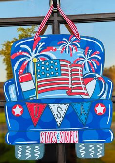 a patriotic sign hanging from the side of a building with fireworks and stars on it