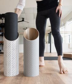 a woman standing next to two large vases on top of a wooden floor in an office