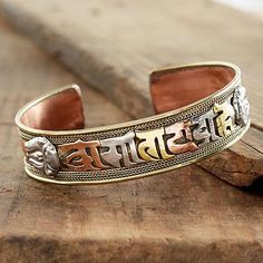 a bracelet with the word buddha written in two different languages on it, sitting on top of a piece of wood