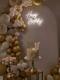 a birthday cake sitting on top of a table next to gold and white balloons that spell happy birthday