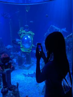 a woman is taking a photo in front of an aquarium