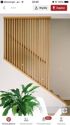 a plant sitting on top of a white table next to a wooden stair case in an empty room