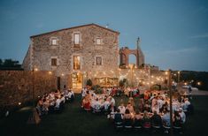 a group of people sitting around a table in front of a building with lights on it