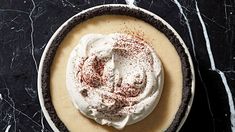 a pie topped with whipped cream and sprinkles on a black table top