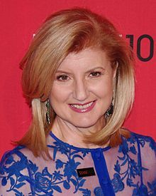 a woman with blonde hair wearing a blue dress and smiling at the camera while standing in front of a red wall