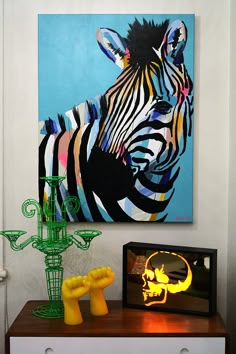 a zebra painting on the wall next to a vase with flowers in it and a lamp