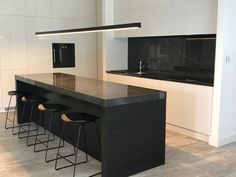 a kitchen with black counter tops and stools next to an island in the middle