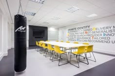 an office with a boxing punching bag in the center and yellow chairs at the end