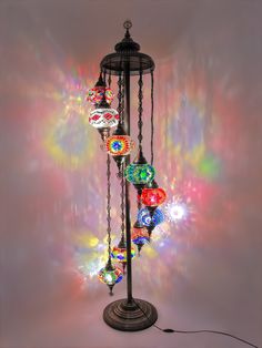 a multicolored light fixture with many lights on it's sides and chains hanging from the top