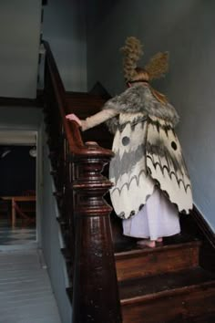 a woman in a butterfly costume walking down the stairs with her hands behind her back