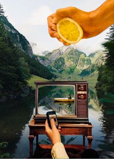 a person is holding an orange slice over a tv with a boat in the water