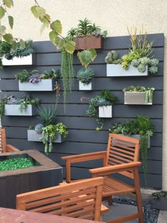 an outdoor seating area with wooden chairs and plants on the wall