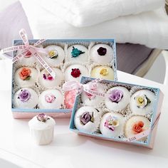 two boxes filled with different types of cupcakes on top of a white table