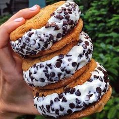 a person holding up a stack of cookies covered in white frosting and chocolate chips