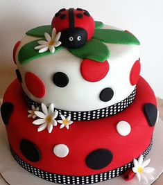 two tiered cake decorated with ladybugs and daisies