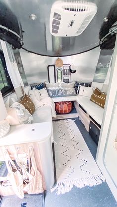 the inside of a camper with couches and pillows on it's floor