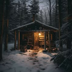 a cabin in the woods with snow on the ground and trees around it at night