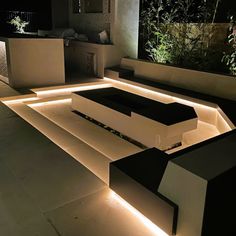 a modern outdoor living area with lighting on the walls and furniture in the center,