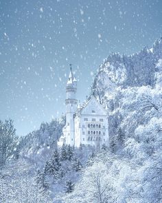 a castle in the middle of a snowy forest with trees and snow falling on it