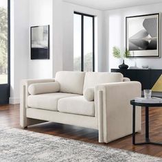 a living room with a white couch and table in front of large glass doors that look out onto the outdoors