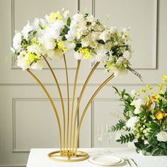 a table topped with white flowers next to a vase filled with yellow and white flowers