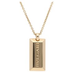 A simple vintage Bulgari Ingot bar pendant necklace set in 18k yellow gold. From the discontinued Ingot collection, the pendant is composed of a bar-shaped yellow gold piece engraved with the signature BVLGARI logo. The pendant hangs from a Bulgari chain, which can be fastened with a secure lobster clasp. Due to the design and size, this piece could be worn for various occasions. The pendant could be worn as a statement piece or stacked up amongst other necklaces. For size reference, the pendant measures approximately 2.6 centimetres in height and 1.3 centimetres in width. The necklace measures 45 centimetres, with a total gross weight of 19.5 grams. Both pendant and chain are signed and hallmarked BVLGARI, 750 (for 18k gold), with Made in Italy and serial number 26970 on the pendant. Last Vintage Bulgari, Gold Bar Pendant Necklace, Bvlgari Logo, Gold Bar Pendant, Double Circle Necklace, Gold Link Necklace, Floral Pendant Necklace, Bar Pendant Necklace, Disc Pendant