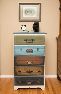 an old dresser with five drawers and a clock on top is painted multicolored