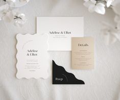 the wedding stationery is laid out on top of the bed sheet, with flowers in the background