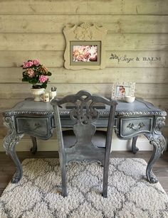 an antique desk with two chairs in front of it and a vase on the table