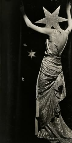 a black and white photo of a woman in a dress with stars on her back