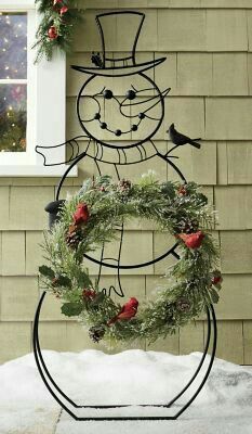 a metal snowman holding a wreath with birds on it