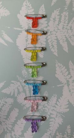 six different colored hair clips are arranged in a row on a floral wallpapered background