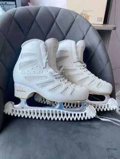 two white roller skates sitting on top of a chair