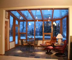 a living room filled with furniture and a fire place under a glass covered ceiling next to a window