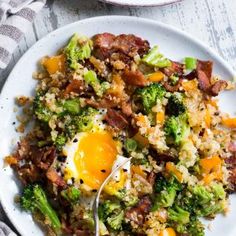 a white plate topped with fried eggs and broccoli next to a bowl of rice