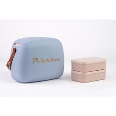 two pink and blue lunch boxes sitting next to each other on a white surface with gold lettering