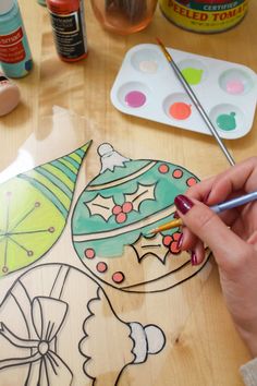 a person is painting a christmas ornament on a wooden table