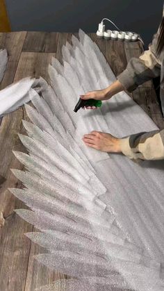 a person is painting an angel wing with white paint on the wood floor next to other items