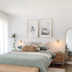 a bed sitting in a bedroom next to two pictures on the wall and a mirror