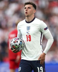 a man holding a soccer ball in his hand and looking off to the side with an intense look on his face