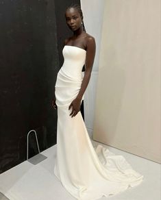 a woman standing in front of a mirror wearing a white dress