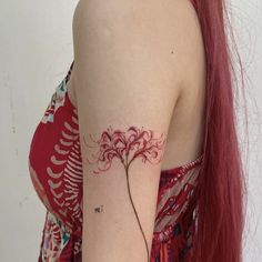 a woman with long red hair has a flower tattoo on her left arm and shoulder