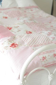 a white bed with pink and white bedspread on it's headboard