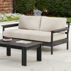 a black and white couch sitting on top of a wooden table next to a garden