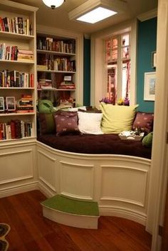 a room with bookshelves and a couch in the corner next to a window