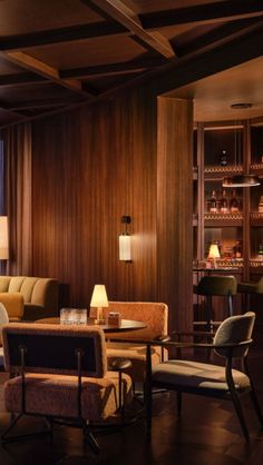 a living room filled with furniture next to a tall wooden shelf full of bottles and glasses