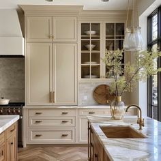 a kitchen with white cabinets and marble counter tops