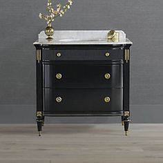 a bathroom vanity with marble top and gold accents on the bottom, against a gray wall