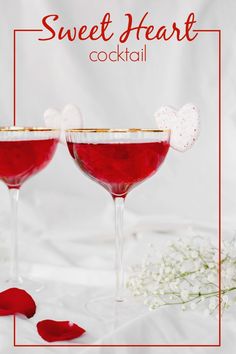 two glasses filled with red liquid and garnished with sugar hearts on the rim